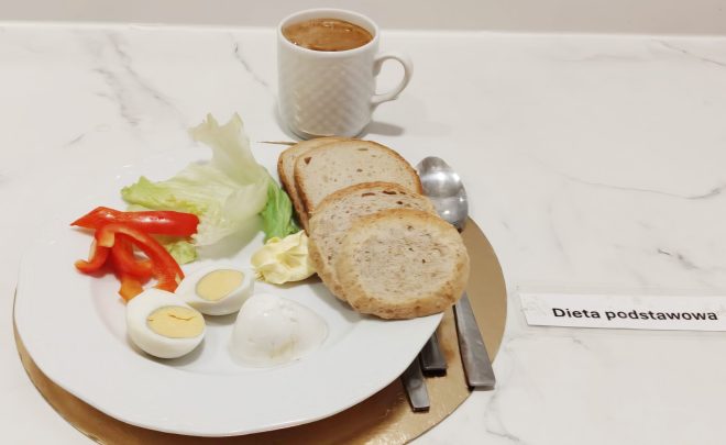 Śniadanie w diecie podstawowej: pieczywo, jajko na twardo, warzywa, masło oraz kawa, podane na talerzu