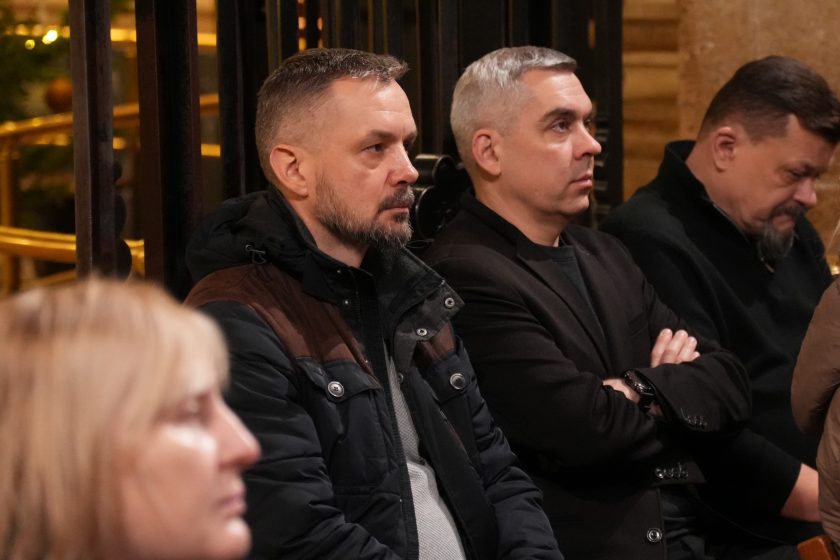 Grupa uczestników spotkania, w tym zakonnicy i świeccy, siedzi w ławkach kaplicy i uważnie patrzy w stronę ołtarza