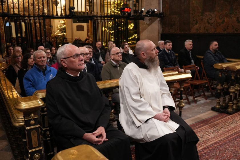 Zbliżenie na uczestników spotkania siedzących w ławkach, w tym zakonników i świeckich współpracowników, skupionych na przebiegu nabożeństwa
