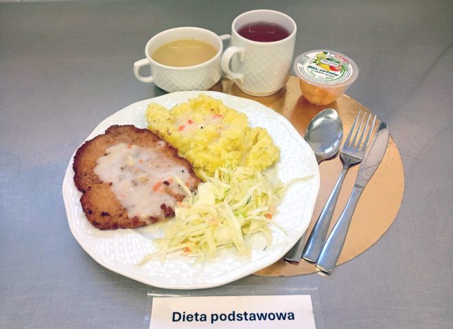 Obiad w diecie podstawowej: kotlet schabowy z sosem, ziemniaki puree, surówka z białej kapusty, podany z zupą jarzynową i kompotem, obok widać mix owoców w osobnym pudełeczku