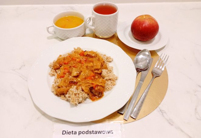 Obiad w diecie podstawowej: kasza podana z gulaszem mięsnym w sosie warzywnym. W zestawie znajduje się również zupa, herbata oraz jabłko jako dodatek owocowy