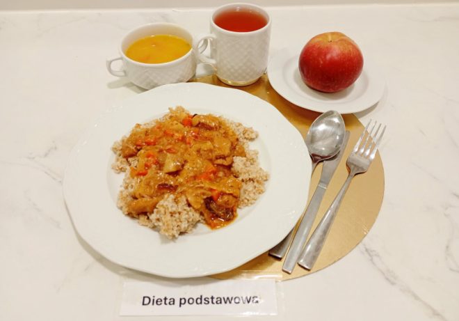 Porcja obiadowa diety podstawowej: kasza podana z gulaszem mięsnym w sosie warzywnym, do tego zupa, herbata oraz jabłko