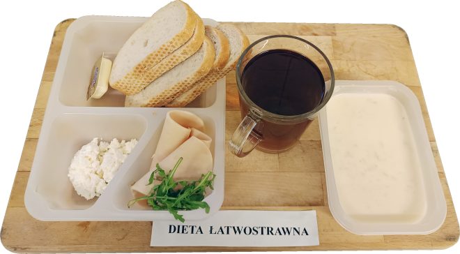Śniadanie na diecie łatwostrawnej: pieczywo pszenne z masłem, twarożek, plasterki drobiowej wędliny z rukolą, herbata oraz jasna zupa mleczna, podane w pojemnikach cateringowych