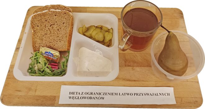 Śniadanie w diecie z ograniczeniem łatwo przyswajalnych węglowodanów: pieczywo razowe, masło, sałata, plasterki ogórka kiszonego, sos jogurtowy, herbata oraz gruszka podane na tacy