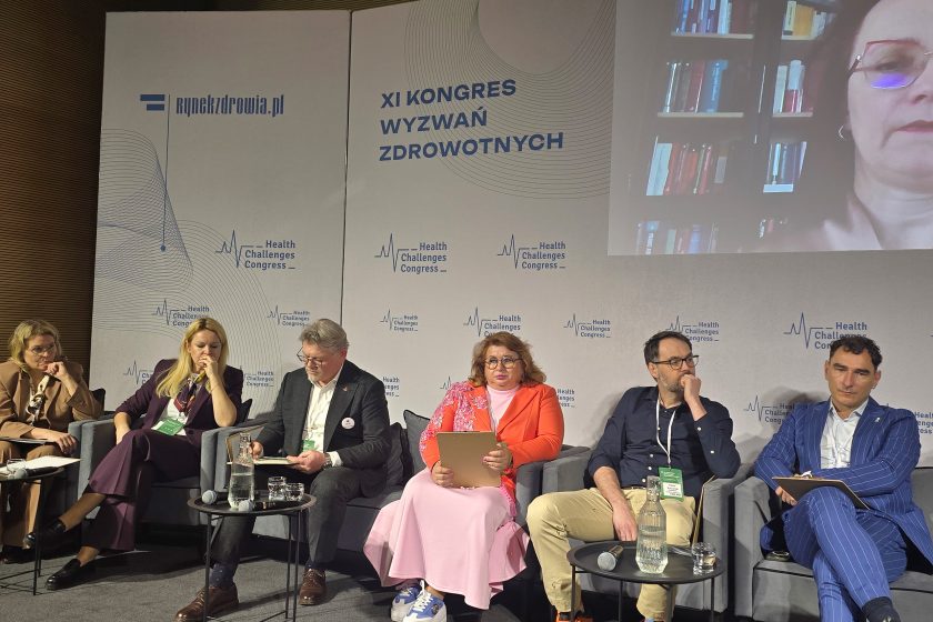 Uczestnicy panelu siedzą w fotelach podczas debaty na XI Kongresie Wyzwań Zdrowotnych; przed nimi stoją stoliki z mikrofonami i wodą, a w tle widoczne jest logo wydarzenia
