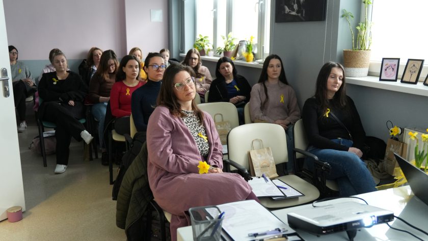 Grupa kobiet uczestniczy w spotkaniu edukacyjnym, siedząc w sali i słuchając wykładu