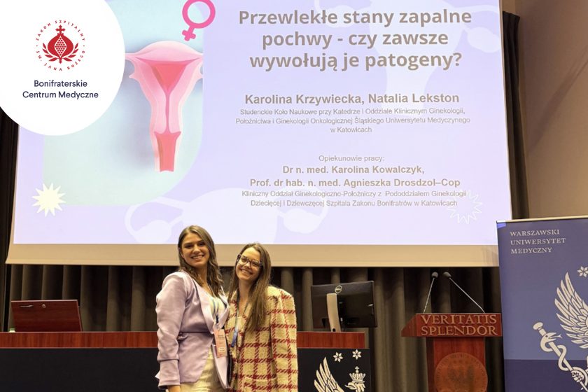Dwie młode kobiety stoją na scenie podczas konferencji medycznej na tle slajdu prezentacji pt. „Przewlekłe stany zapalne pochwy – czy zawsze wywołują je patogeny?”. Uśmiechnięte prelegentki pozują przed ekranem, obok mównicy z napisem „Veritatis Splendor” oraz logotypów uczelni i Bonifraterskiego Centrum Medycznego