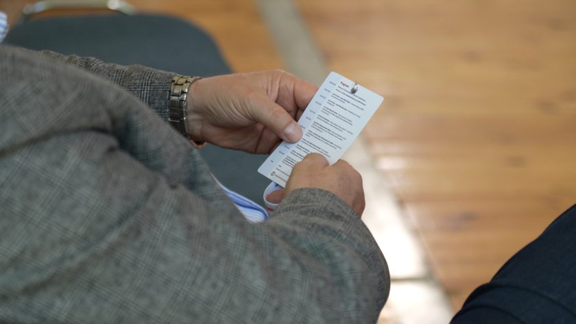 Zbliżenie na dłonie uczestnika konferencji trzymającego program wydarzenia. Widoczny identyfikator oraz harmonogram spotkań podkreślają organizacyjny charakter Bonifraterskich Spotkań z Rehabilitacją