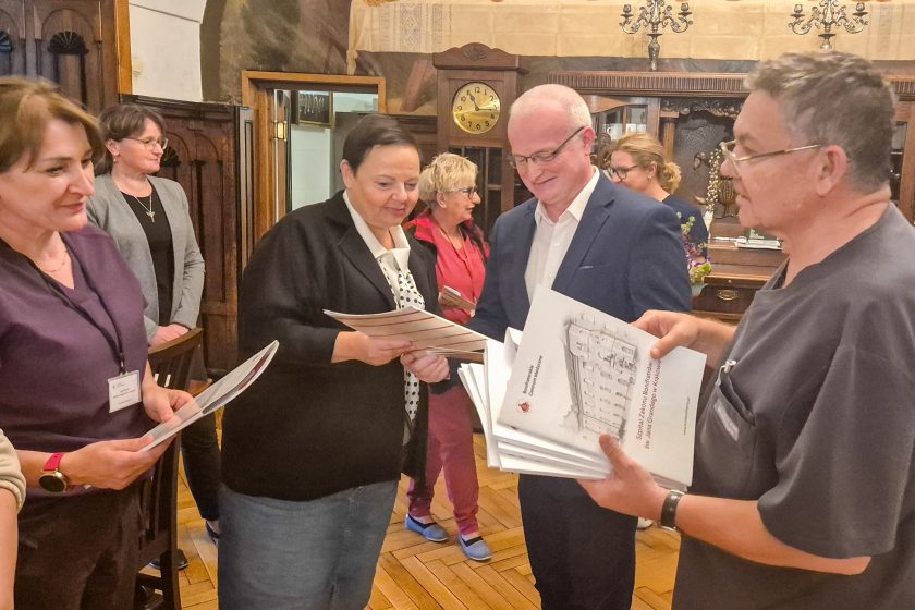 Uczestnicy spotkania oglądają i odbierają egzemplarze publikacji poświęconej historii szpitala Bonifratrów w Krakowie