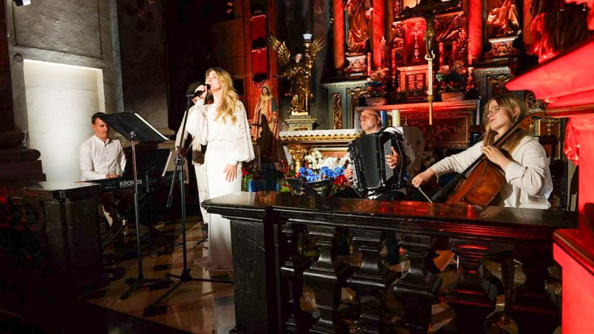 Wokalistka wraz z zespołem wykonuje koncert w zabytkowym wnętrzu świątyni. Towarzyszą jej akordeonista, wiolonczelistka oraz pianista, a scena została zaaranżowana przed głównym ołtarzem
