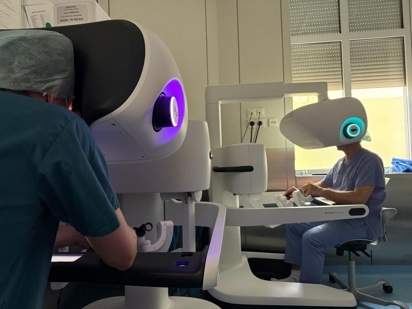 Trwa operacja z wykorzystaniem robota chirurgicznego da Vinci. Nad pacjentem znajdują się cztery zrobotyzowane ramiona zabezpieczone sterylnymi osłonami, a personel medyczny obserwuje przebieg zabiegu na monitorze wyświetlającym obraz wnętrza operowanego obszaru. Całość odbywa się na nowoczesnej sali operacyjnej wyposażonej w zaawansowany sprzęt medyczny