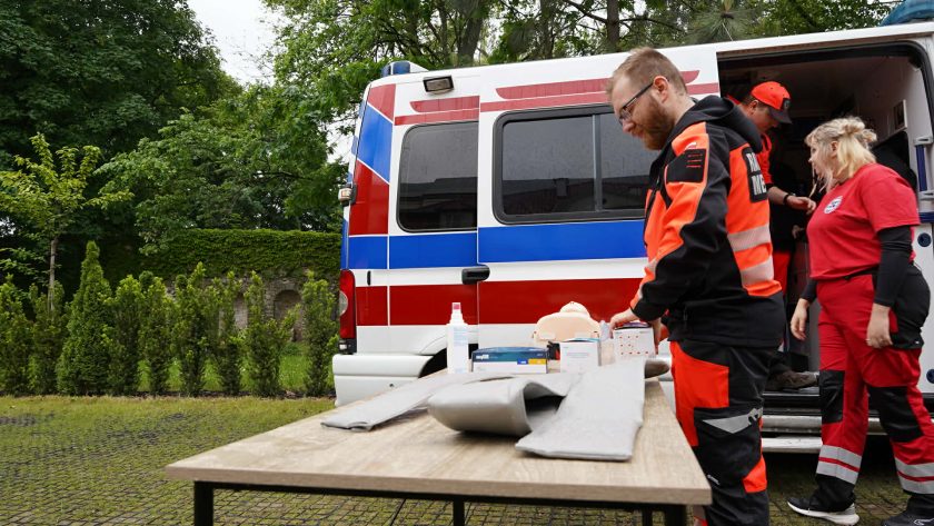 Ratownicy medyczni przygotowują stanowisko do pokazów pierwszej pomocy przy ambulansie zaparkowanym na terenie wydarzenia