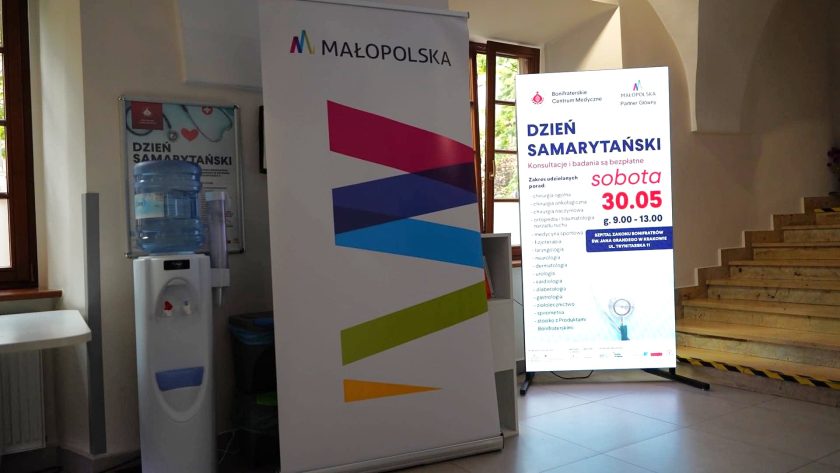 W holu Bonifraterskiego Centrum Medycznego ustawiono roll-up Województwa Małopolskiego oraz podświetlany ekran informacyjny promujący Dzień Samarytański. Obok znajduje się dystrybutor wody, a w tle schody prowadzące na wyższe kondygnacje budynku