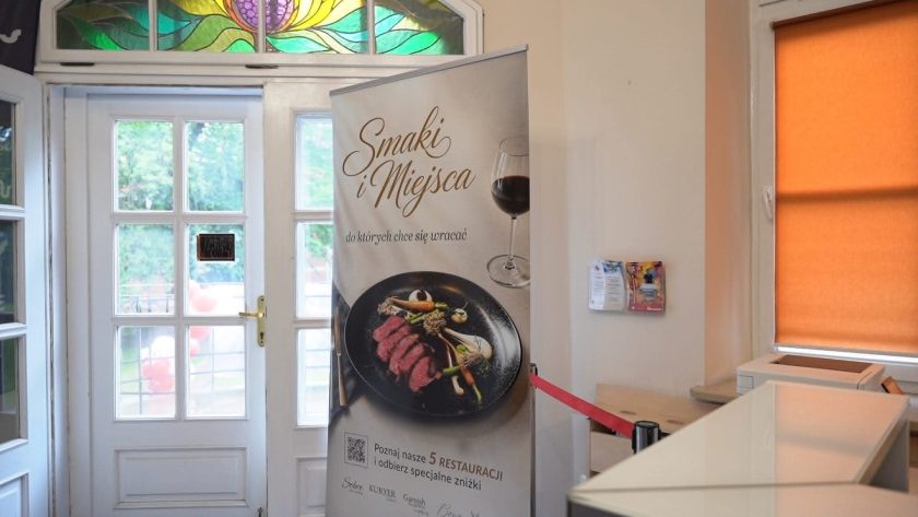 Roll-up promujący akcję „Smaki i Miejsca, do których chce się wracać” ustawiony przy wejściu do budynku Bonifraterskiego Centrum Medycznego