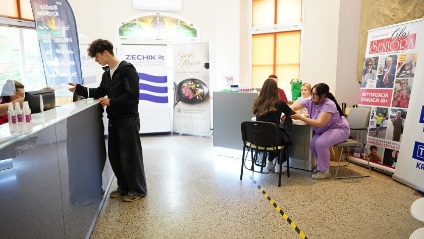 Hol Bonifraterskiego Centrum Medycznego podczas wydarzenia profilaktycznego. Przy recepcji rejestruje się młody uczestnik, a w tle pielęgniarki wykonują badania i konsultacje
