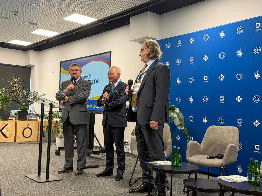 Uczestnicy panelu dyskusyjnego na scenie konferencyjnej. Eksperci prowadzą rozmowę na temat znaczenia badań przesiewowych i wczesnego wykrywania nowotworów jelita grubego wśród mieszkańców Krakowa