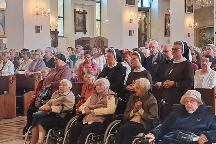 Licznie zgromadzeni wierni podczas nabożeństwa w kościele. W pierwszych rzędach znajdują się seniorzy, w tym osoby poruszające się na wózkach.